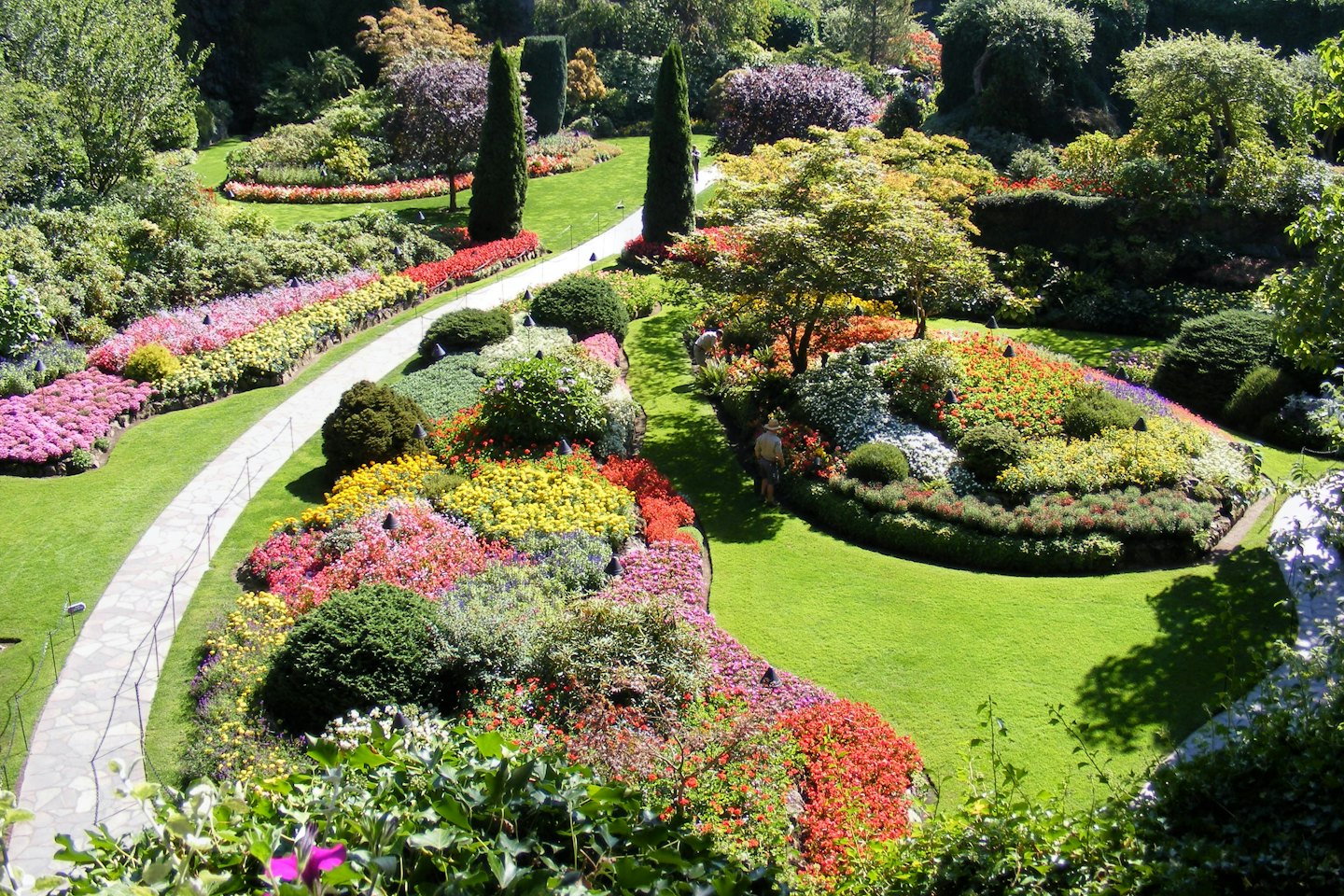 Stone paths wind through colorful flower beds in a botanical garden.